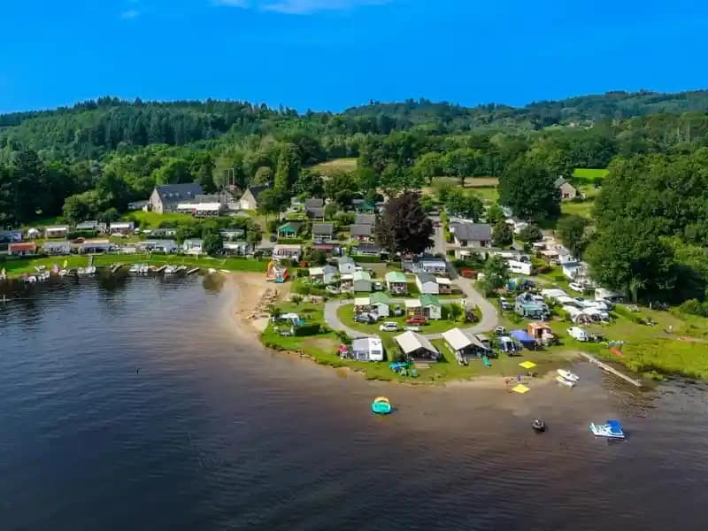 Vue aérienne d’un camping en bord de lac entouré par la nature