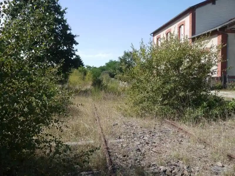 Ancienne gare et mémoire du patrimoine ferroviaire Ancienne gare avec voie ferrée désaffectée progressivement reprise par la végétation