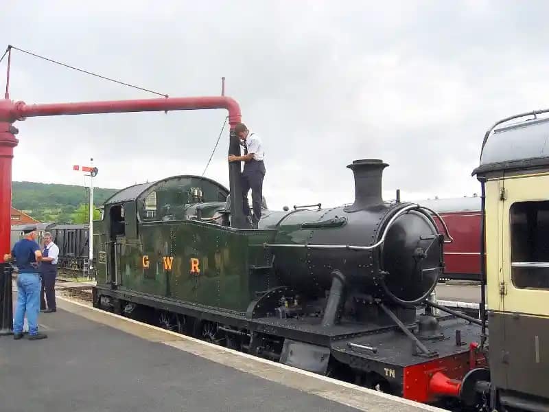 Locomotive à vapeur historique effectuant un ravitaillement en eau