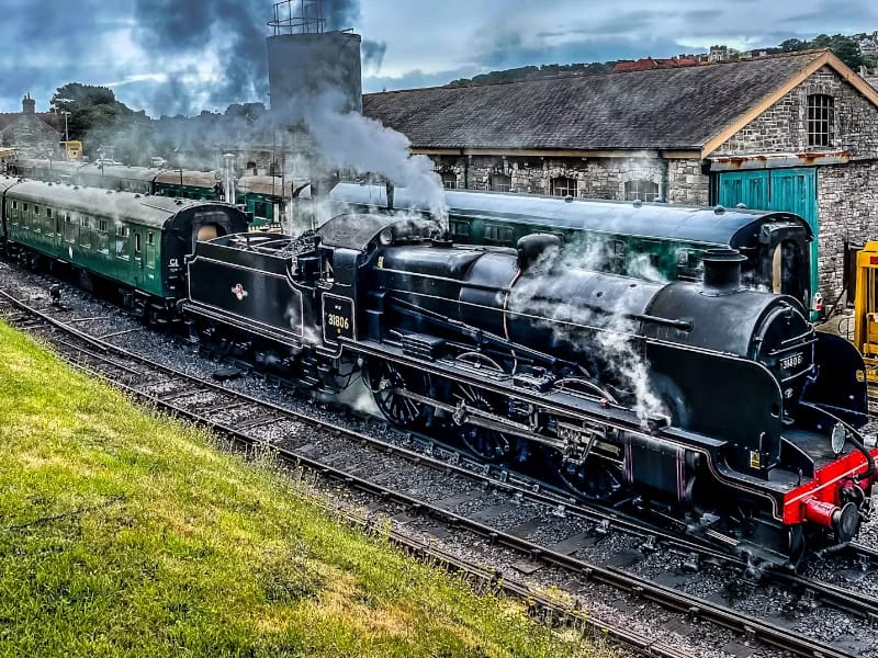 Train à vapeur et patrimoine ferroviaire Locomotive à vapeur avec voitures voyageurs dans un site ferroviaire historique