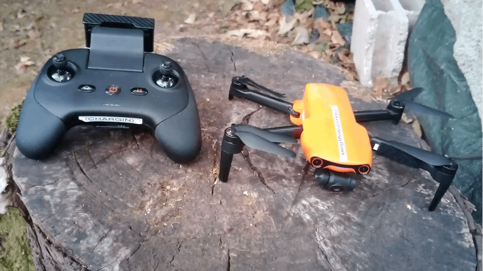 Drone professionnel et radiocommande posés sur une souche en extérieur